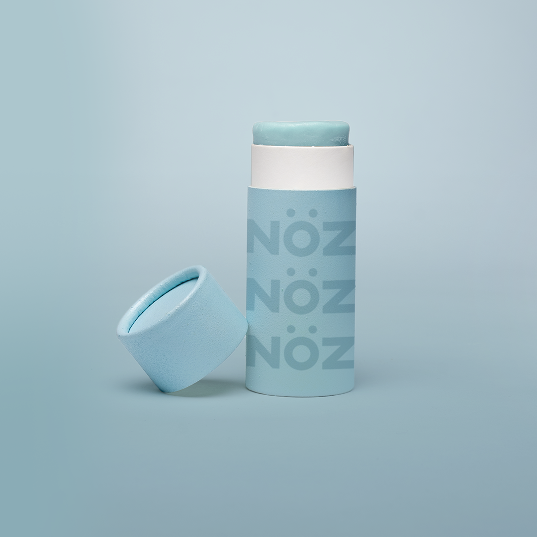 A blue Nöz sunscreen stick in sustainable cardboard packaging. The stick is mineral sunscreen that is reef-safe, waterproof and dermatologist recommended.