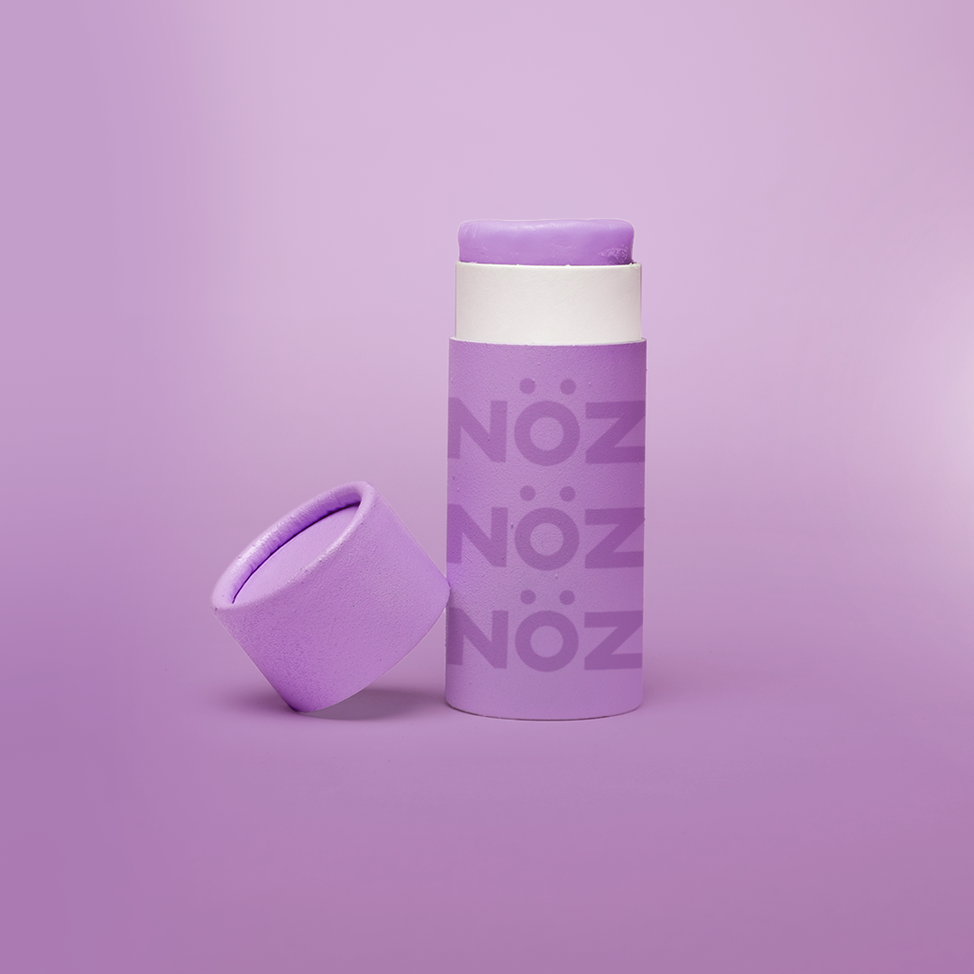 A purple Nöz sunscreen stick in sustainable cardboard packaging. The stick is mineral sunscreen that is reef-safe, waterproof and dermatologist recommended.