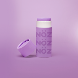 A purple Nöz sunscreen stick in sustainable cardboard packaging. The stick is mineral sunscreen that is reef-safe, waterproof and dermatologist recommended.