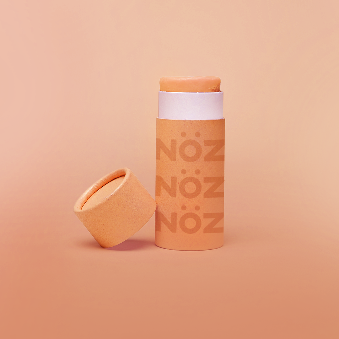 A orange Nöz sunscreen stick in sustainable cardboard packaging. The stick is mineral sunscreen that is reef-safe, waterproof and dermatologist recommended.