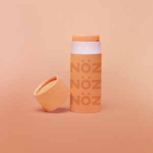 A orange Nöz sunscreen stick in sustainable cardboard packaging. The stick is mineral sunscreen that is reef-safe, waterproof and dermatologist recommended.