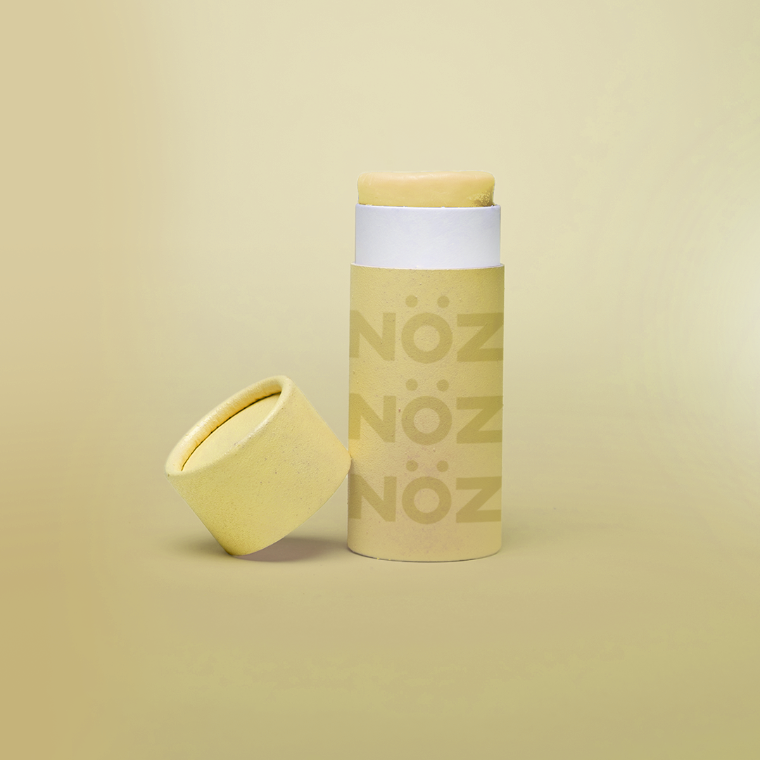 A yellow Nöz sunscreen stick in sustainable cardboard packaging. The stick is mineral sunscreen that is reef-safe, waterproof and dermatologist recommended.