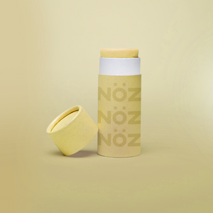 A yellow Nöz sunscreen stick in sustainable cardboard packaging. The stick is mineral sunscreen that is reef-safe, waterproof and dermatologist recommended.