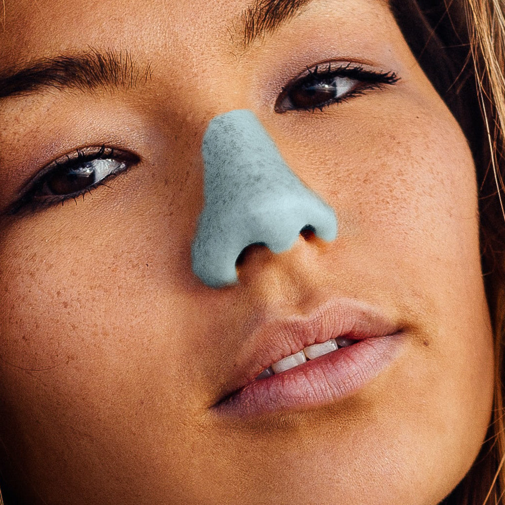 A close up of a woman with blue Nöz sunscreen on her nose imitating "lifeguard nose".